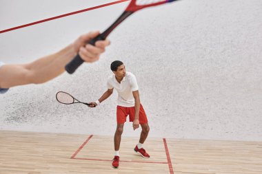 Spor giyim sektöründe Afrika kökenli Amerikalı bir adam squash kortunun içinde arkadaşıyla oynuyor.