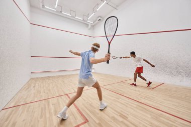 Spor giyim sektöründe iki çok kültürlü oyuncu saray içinde squash oynuyor, aktif bir yaşam tarzı.