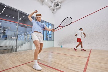Spor giyim sektöründeki ırklar arası arkadaşlar mahkeme içinde squash oynuyorlar, motivasyon ve spor.