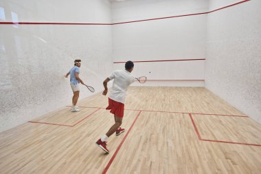 Spor giyiminde çok kültürlü arkadaşlar mahkemede squash oynuyorlar, motivasyon ve spor.