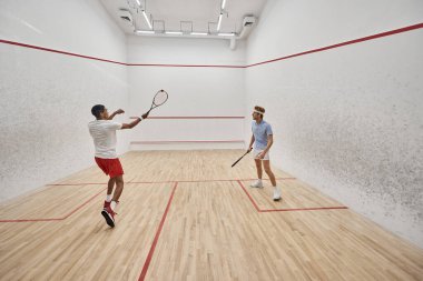Spor giyim sektöründe çok kültürlü erkekler mahkeme içinde squash oynuyorlar, motivasyon ve spor.