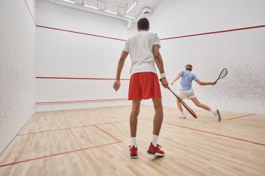 Spor giyim sektöründe ırklar arası aktif erkekler mahkeme içinde squash, meydan okuma ve motivasyon oynuyorlar.