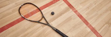 İç saha sahasının zemininde squash topu ve raketi, motivasyon ve kararlılık pankartı