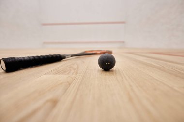 Beyaz duvarları, motivasyonu ve kararlılığı olan squash kortunun içinde top ve raket.
