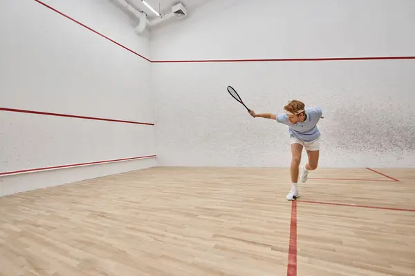 stock image young and active redhead man in sportswear playing squash inside of court, challenge and motivation