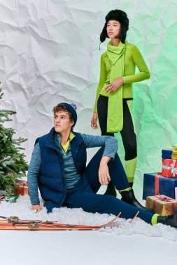 Kış mevsiminde ırklar arası çiftler karlı stüdyoda hediyelerin ve Noel ağacının yanından uzağa bakarlar.