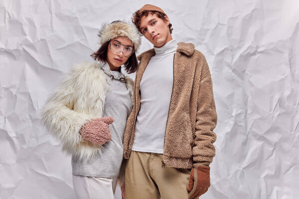 fashion lookbook concept, interracial models in winter attire posing on white textured background