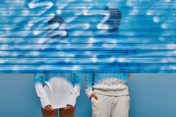 пара в белых вязаных свитерах за синим замороженным пластиковым листом в студии, зимняя концепция моды