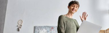 Transseksüel blog yazarının bilgisayarında video çağrısı var ve modern apartmanda duruyor, etkili pankart