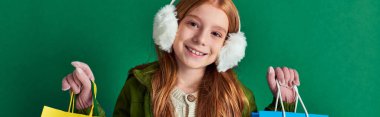 holiday season banner, happy preteen girl in winter outfit and ear muffs holding shopping bags clipart