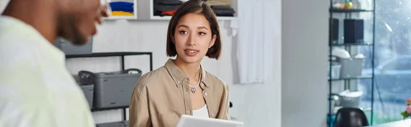 stock image asian woman discussing new business project with african american colleague in print studio, banner