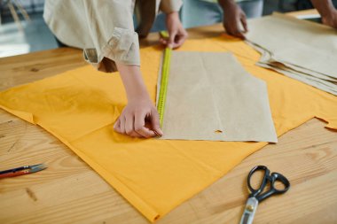 Baskı stüdyosundaki dikiş kalıplarını ölçen yaratıcı çok kültürlü moda tasarımcılarının kırpılmış görüntüsü