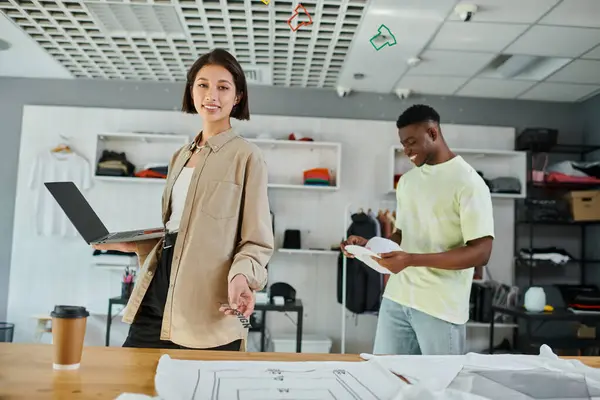 stock image happy asian designer with laptop and text template near african american man in print studio