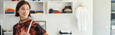 Genç ve başarılı Asyalı moda tasarımcısı tekstil baskı stüdyosunda gülümsüyor.