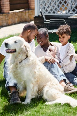 Mutlu Afro-Amerikan ailesinin aile portresi köpek bahçesinde otururken harika vakit geçiriyor.