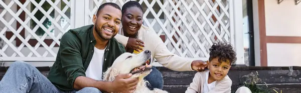 家族の時間バナー 幸せなアフリカ系アメリカ人の両親と息子は家の裏庭で犬と遊んでいます — ストック写真