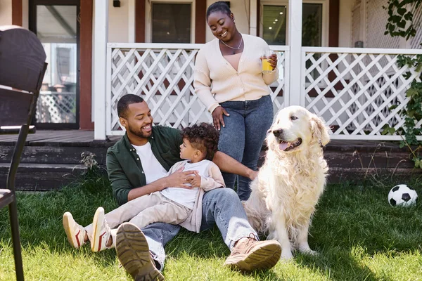 近代的な子育て 陽気なアフリカ系アメリカ人の父親と息子は 裏庭で女性や犬の近くで遊んでいます — ストック写真