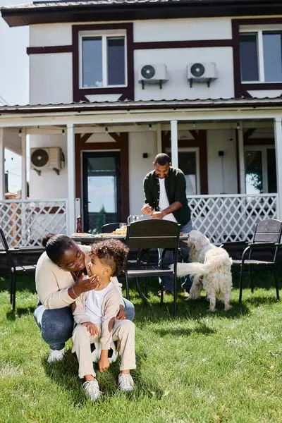 幸せなアフリカ系アメリカ人の母親は 家の裏庭に夫の近くのサッカーに座って息子を抱きしめます — ストック写真
