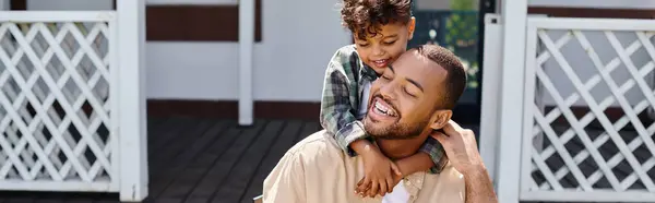 stock image positive african american kid hugging father while having bbq on backyard of house, banner