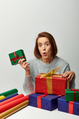 Vay canına, kışın süveter giyen kadın elinde gri renkli hediye kağıdının yanında Noel hediyesi tutuyor.