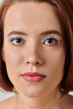 close up portrait of woman with holiday makeup looking at camera, shiny eye shadow and red lipstick clipart