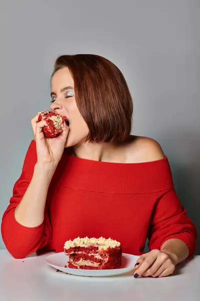 stock image young woman in red attire biting delicious piece of bento cake on grey background, Happy Birthday