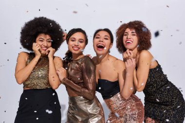 Güzel, şık Afro-Amerikan kadınları konfeti yağmuru ve moda altında canlı giysiler içinde parti yapıyorlar.