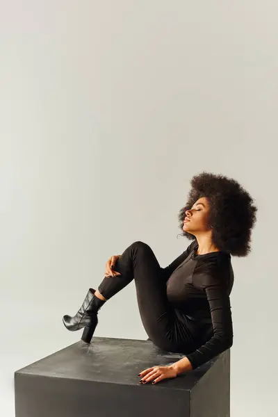 穿着黑色吸引人的紧身衣坐在黑色立方体上的迷人的非洲裔美国女人 时尚概念 — 图库照片