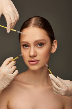 estheticians in medical gloves holding syringes near young woman on grey background, collagen clipart
