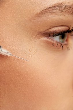 Hyaluronik asitle yakın çekim yap ya da gri arka planda genç bir kadının yüzüne yakın dolgu yap.