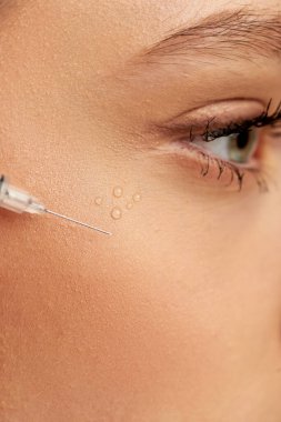 close up shot of syringe with hyaluronic acid or filler near face of young woman on grey background clipart
