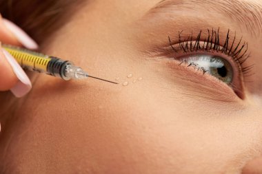 close up of syringe with hyaluronic acid or filler near face of young woman on grey background clipart