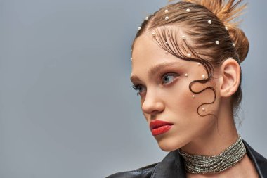Saçlarında inci tokalar ve gri arkaplanda kırmızı dudaklar olan göz kamaştırıcı genç modelin portresi