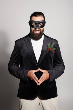 Maskeli balo, karnaval maskeli neşeli sakallı adam ve gri arka planda zarif bir kıyafet.