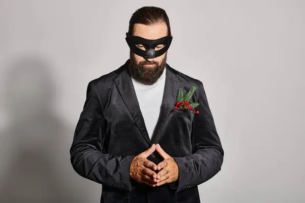 stock image Masquerade ball, concentrated bearded man in carnival mask and elegant formal wear on grey backdrop