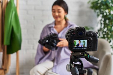 Atölye, moda vlog 'unda modaya uygun kıyafetleri olan yetenekli Asyalı stilist yakınındaki dijital kameraya odaklan