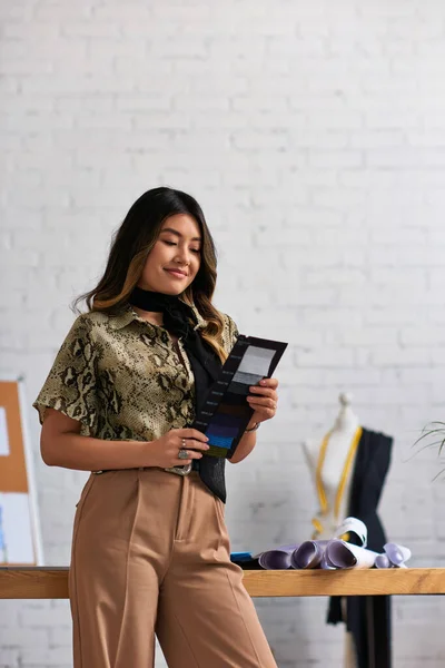 stock image cheerful asian clothes stylist holding color swatches in private fashion atelier, inspiration