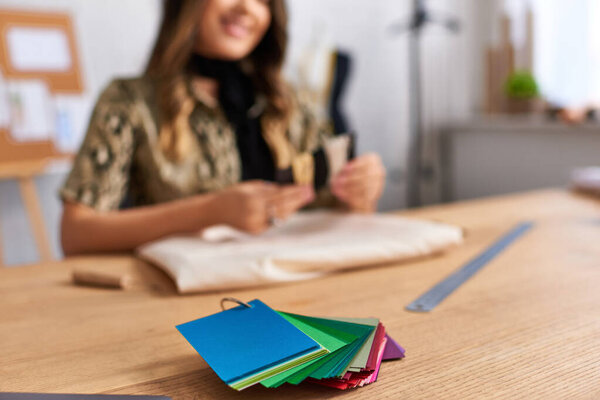 селективный фокус цветных образцов рядом с обрезанным дизайнером улыбаясь на размытом фоне в ателье