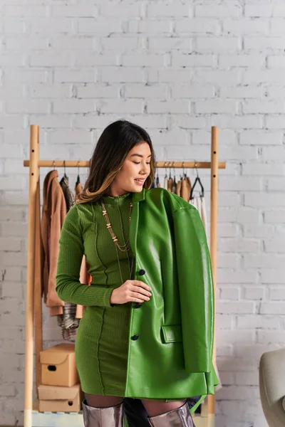 快乐的亚洲设计师穿着时髦的绿色皮夹克装扮在现代工作室 时尚行业 — 图库照片