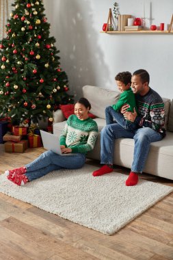 Modern Afro-Amerikan ailesinin dizüstü bilgisayardan Noel filmi izlerken çekilmiş dikey bir fotoğrafı.