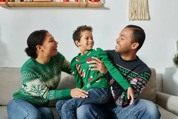 stock image cheerful african american parents with their kid sitting on lap wearing warm Christmas sweaters