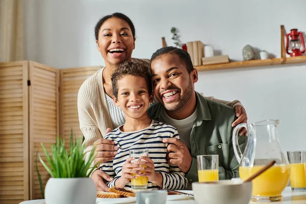 アフリカ系アメリカ人の家族が 朝食のテーブルでカメラで温かく笑顔で抱きしめています — ストック写真
