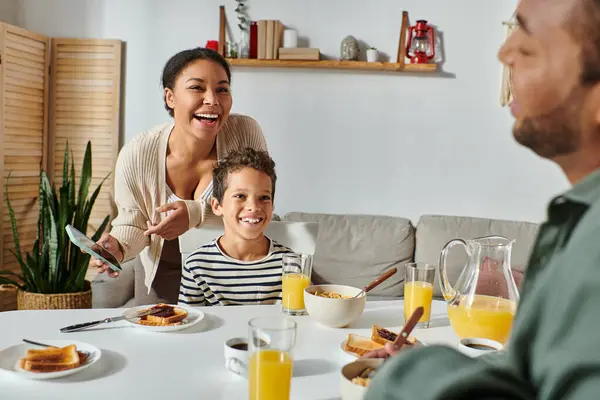 アフリカ系アメリカ人の母親と息子に焦点を当て 朝食時にぼやけた父親に笑顔で — ストック写真