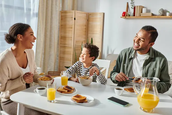 美しい現代アフリカ系アメリカ人の家族がおいしい朝食を食べながら話したり笑ったり — ストック写真