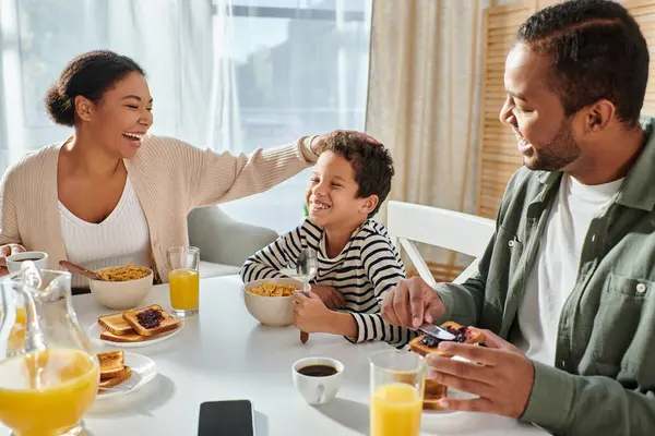 カジュアルなホームウェアで幸せな現代アフリカ系アメリカ人の家族は 朝食テーブルで一緒に楽しんでいます — ストック写真