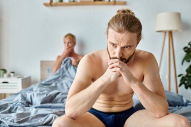Hayal kırıklığına uğramış iç çamaşırlı eşcinsel erkek arkadaşının yanında oturuyor yatak odasında bulanık bir geçmişi var.