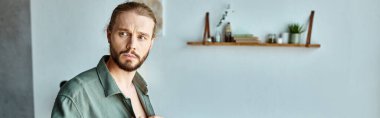 portrait of thoughtful and bearded adult man looking away in bedroom at home, horizontal banner clipart