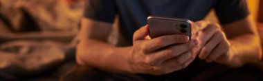 Yetişkin bir adamın gece yatak odasında cep telefonu kullanırken çekilmiş görüntüsü, yatay pankart.