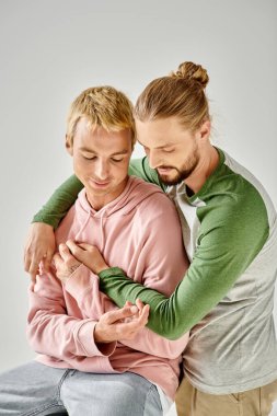 Romantik ve şehvetli eşcinsel çift şık giyinmiş, gri arka plana sarılıyorlar, gay aşkı.