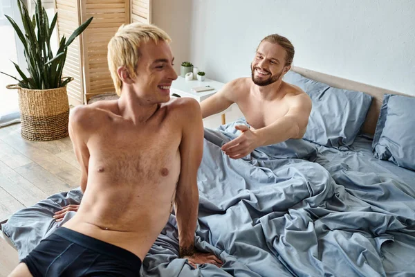 快乐的 满脸胡须的同性恋男子 他张开双手 笑着男朋友坐在床上 — 图库照片
